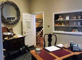 Habitación de hotel con escritorio, teléfono, espejo y repisa con adornos.