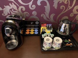 A coffee maker, a tray with coffee pods, milk cartons, and a teapot on a table.