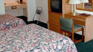 Et hotelværelse med to senge, et skrivebord med fjernsyn, en stol og et spejl.