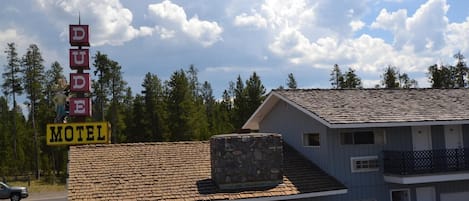 A motel with a stone chimney, a sign reading "DUDE MOTEL," and a two-story building with a blue exterior.