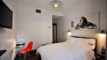 Une chambre d’hôtel équipée d’un lit, d’un bureau, d’une chaise, d’une télévision et d’une œuvre d’art accrochée au mur.