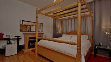 Una cama con dosel de madera, una mesita de noche pequeña, una chimenea, un espejo y una alfombra roja.