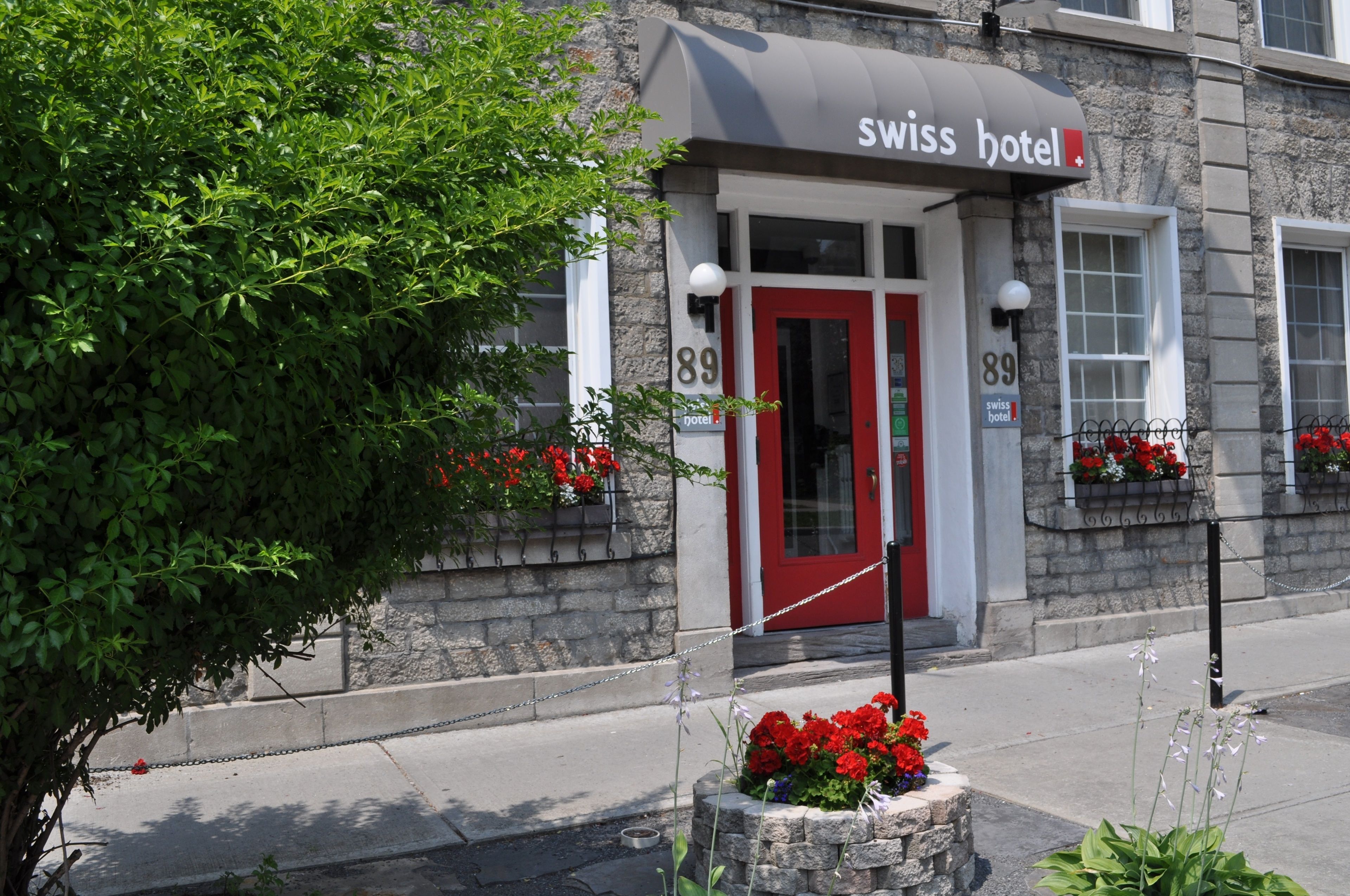 Un hotel con una puerta roja y un letrero que dice "Swiss Hotel".