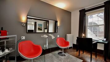A modern room with two red chairs, a glass table, a mirror, and a view of a snowy landscape through a window.