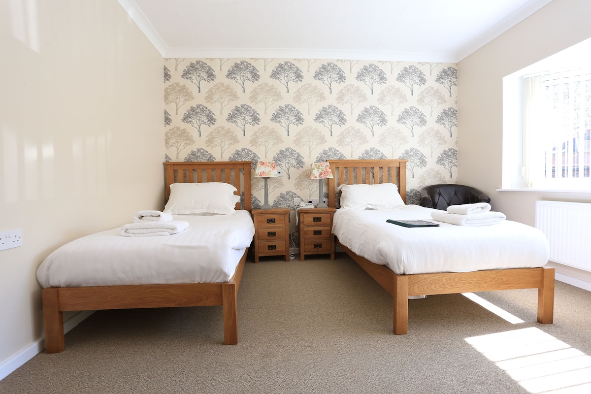 A bedroom with two wooden beds, a window, and a radiator.