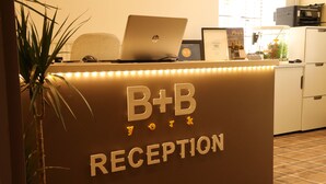 A reception desk with a laptop, framed certificates, and a potted plant. - B+B York (York)