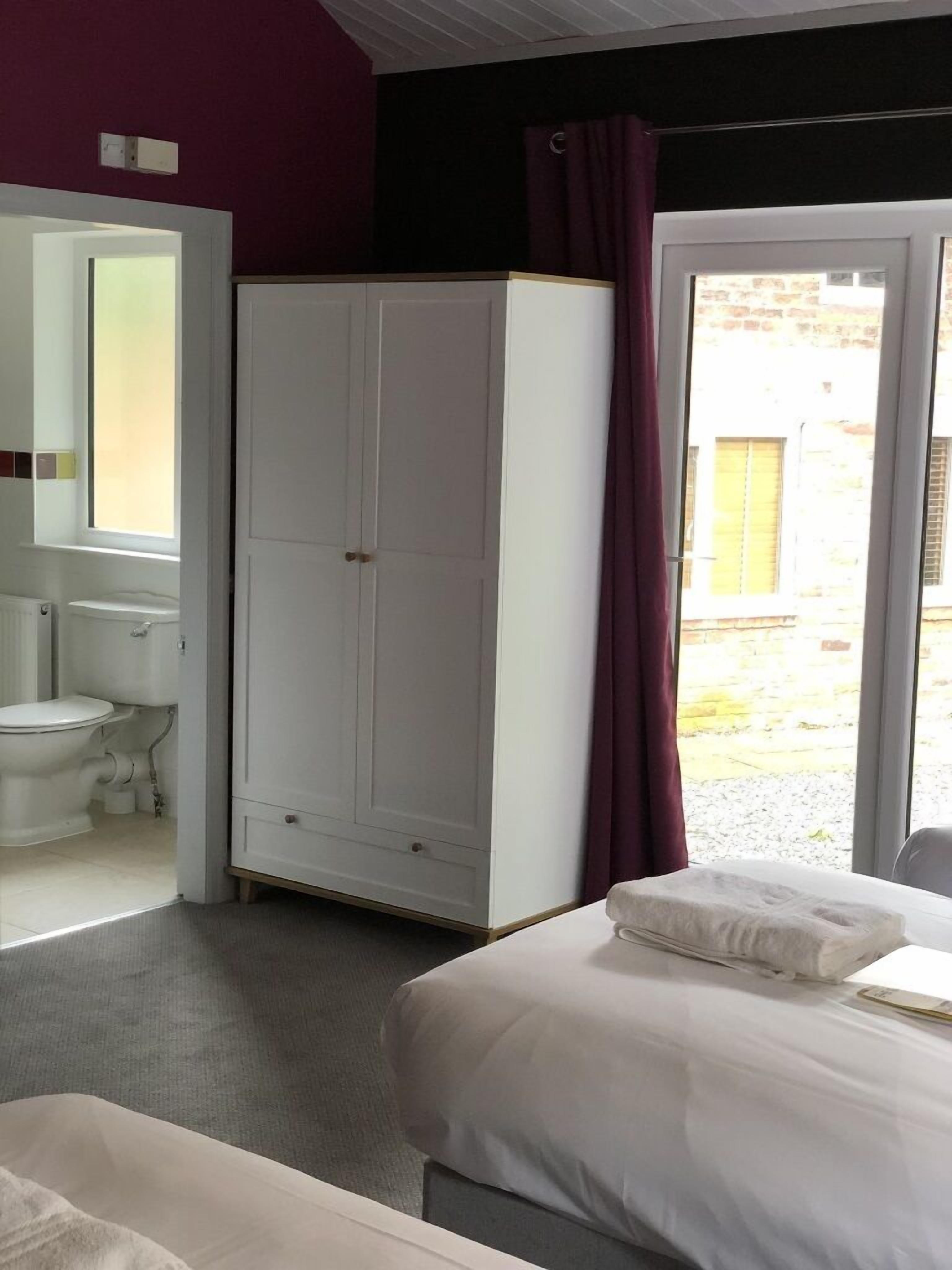 Un dormitorio con cama, armario, baño con inodoro y lavabo, y vistas al exterior.