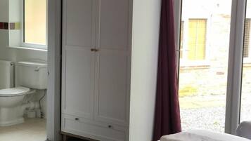 Un dormitorio con cama, armario, baño con inodoro y lavabo, y vistas al exterior.