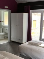 Un dormitorio con cama, armario, baño con inodoro y lavabo, y vistas al exterior.
