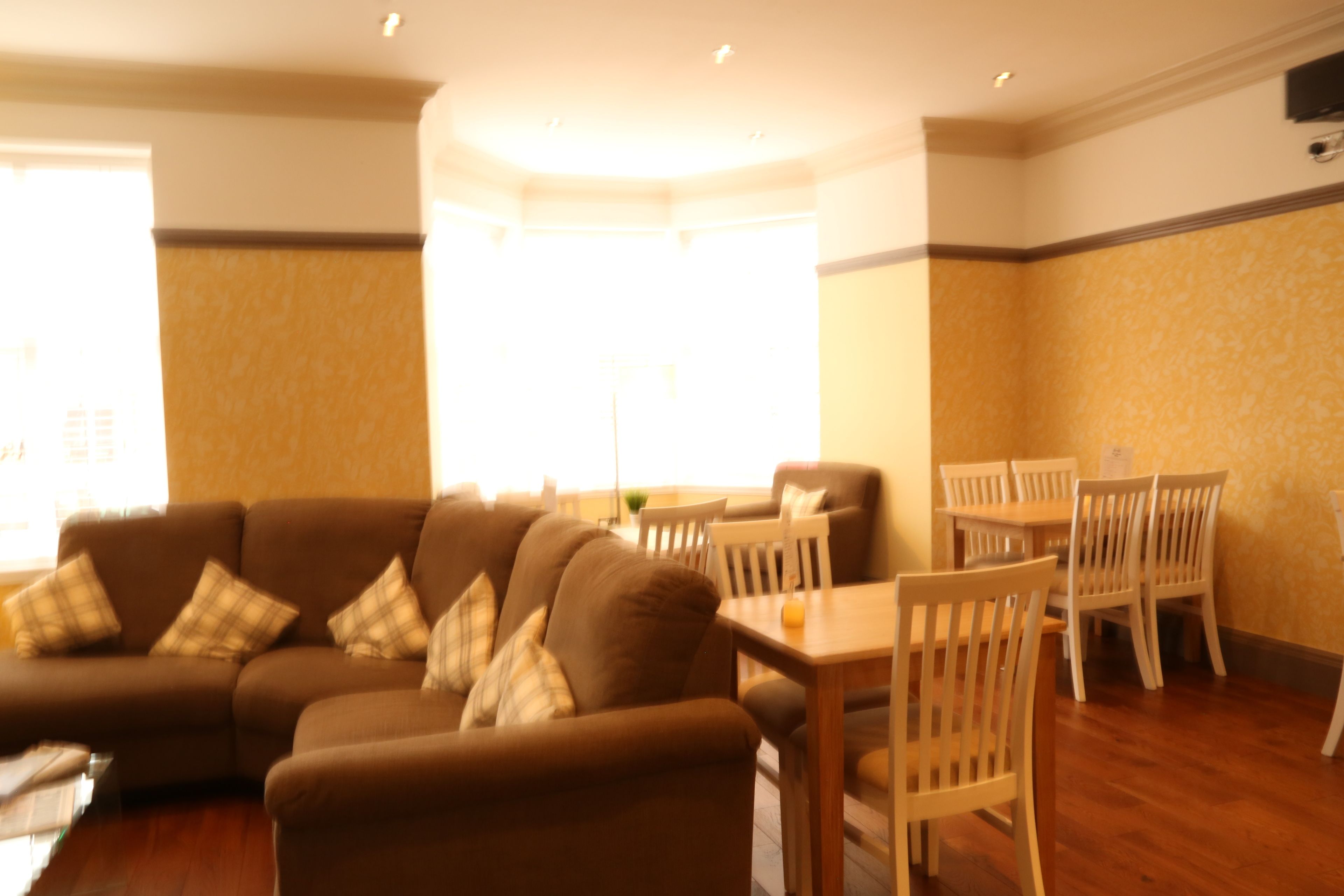 Una sala de estar con un sofá marrón, sillas blancas y una mesa de madera.