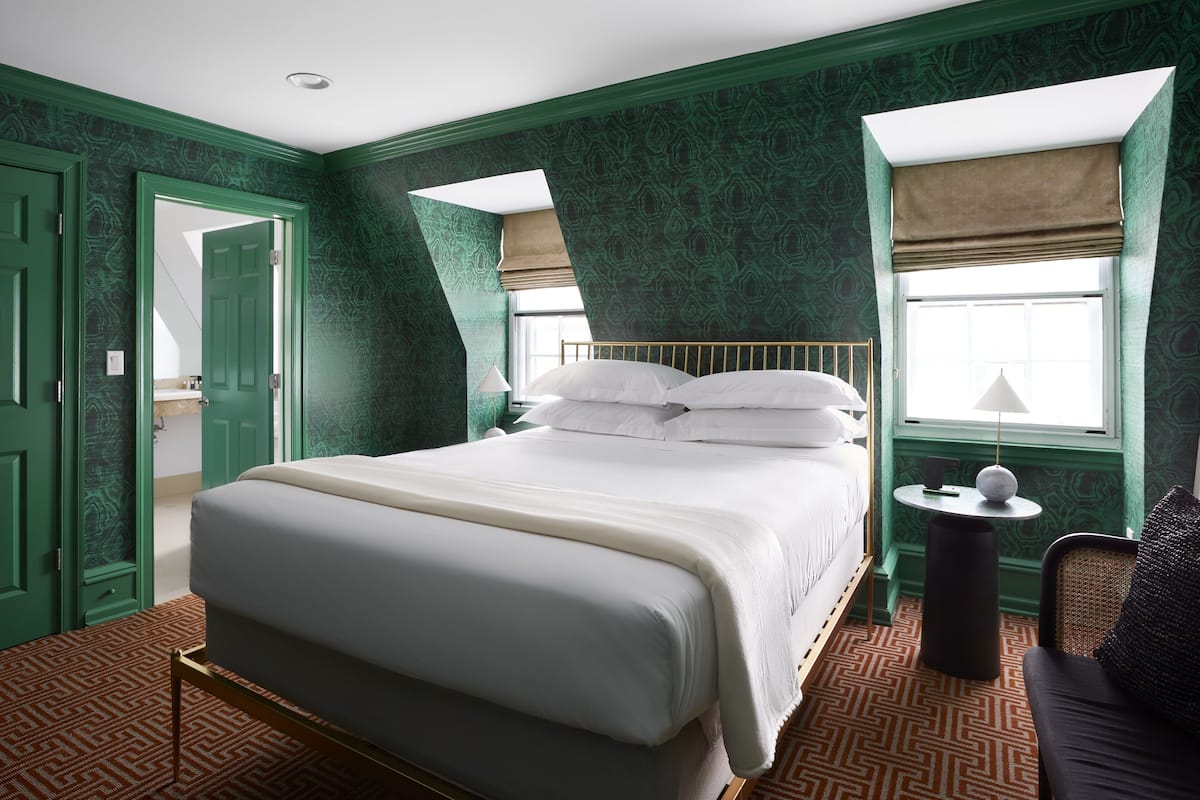 A room with a large bed, a small table, and a chair.
