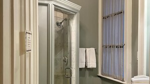A bathroom with a glass-enclosed shower, a toilet, a sink, and a window with curtains. - The College Club of Boston (Boston)