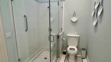 Et moderne badeværelse med bruseniche, toilet og håndvask.