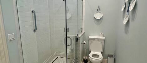 Un baño moderno con ducha de vidrio, inodoro y lavamanos.