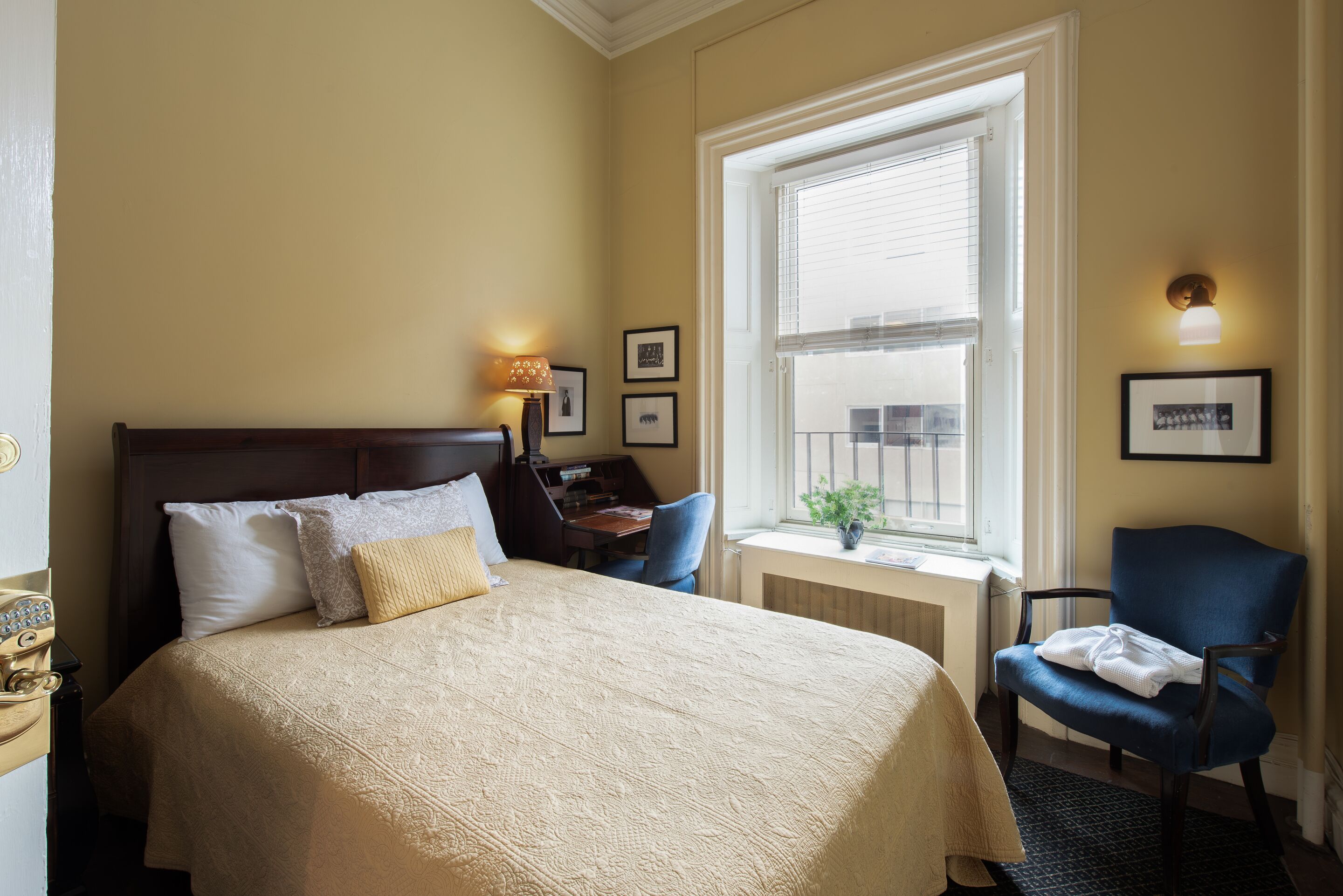 Une chambre d’hôtel avec un grand lit, un bureau, une chaise et une fenêtre avec des stores.