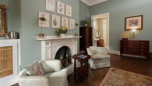 A living room with a fireplace, two armchairs, a small table, and a wooden dresser. - The College Club of Boston (Boston)