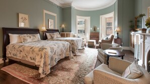 A spacious bedroom with a large bed, two smaller beds, a sitting area with a sofa and armchairs, and a fireplace. - The College Club of Boston (Boston)