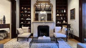A living room with a fireplace, two sofas, a coffee table, and a bookshelf filled with decorative items. - Clarendon Square (Boston)