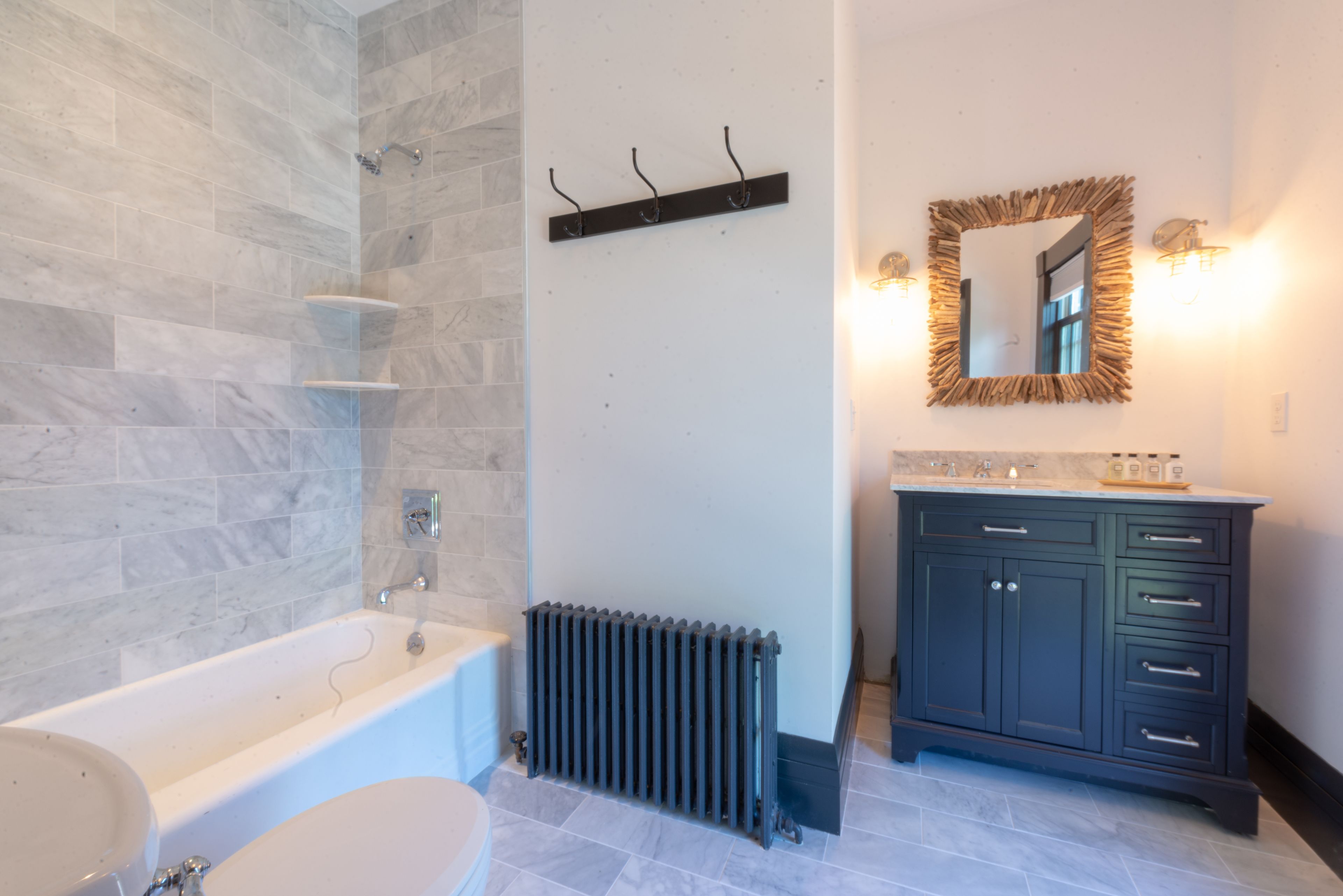 A bathroom with a bathtub, a toilet, a sink, a mirror, and a radiator.