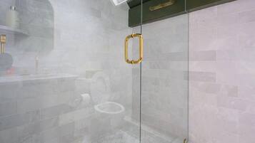 Een moderne badkamer met een douchecabine van glas, een dakraam en een wand betegeld met marmer.