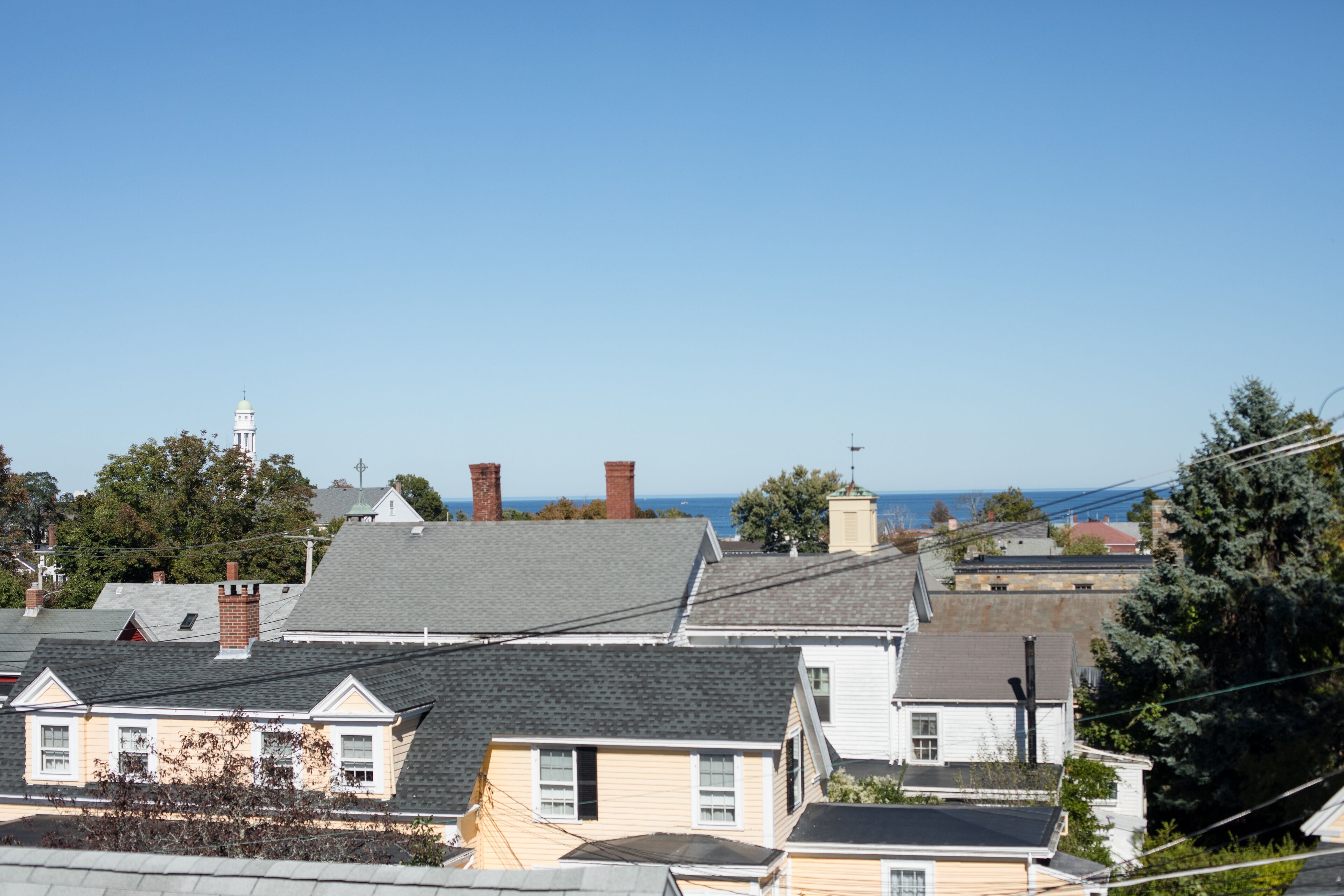 A residential area with houses, a lighthouse, and a view of the ocean.