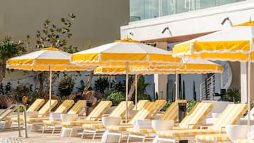 A pool area with lounge chairs and yellow umbrellas.