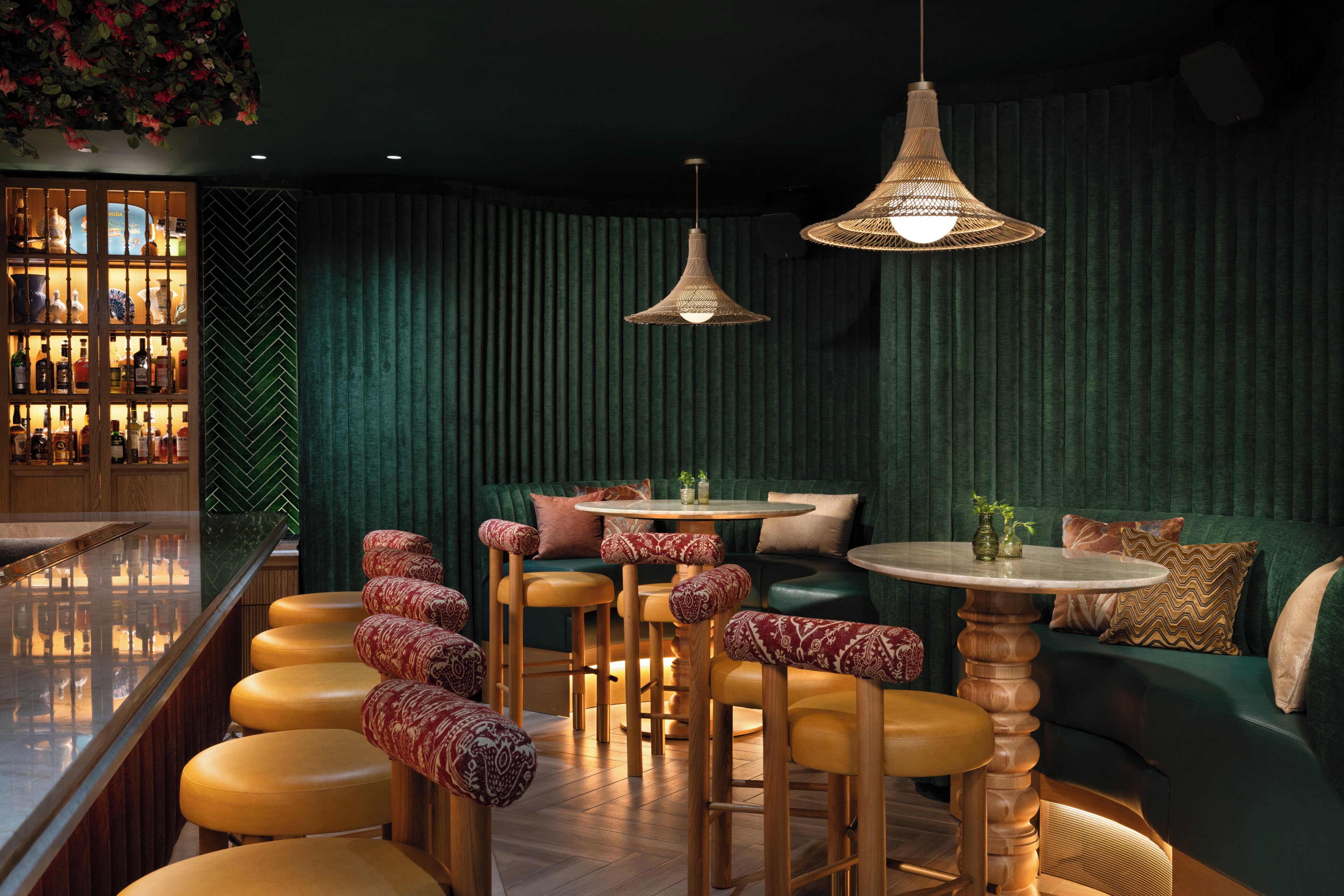 A bar area with stools, a round table, and hanging wicker lamps.