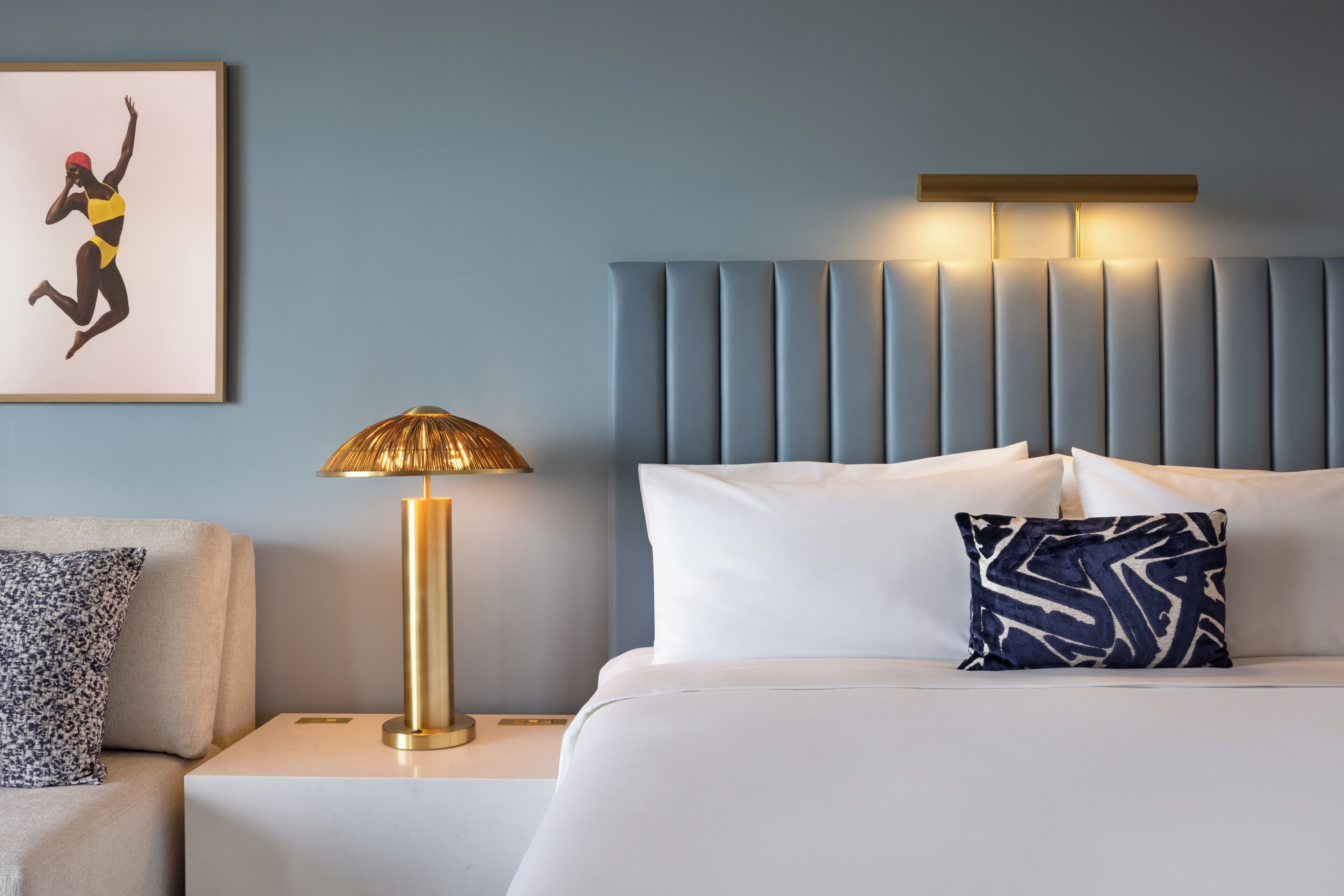 Une chambre d’hôtel avec un lit, une table de chevet, une lampe et un tableau encadré au mur.
