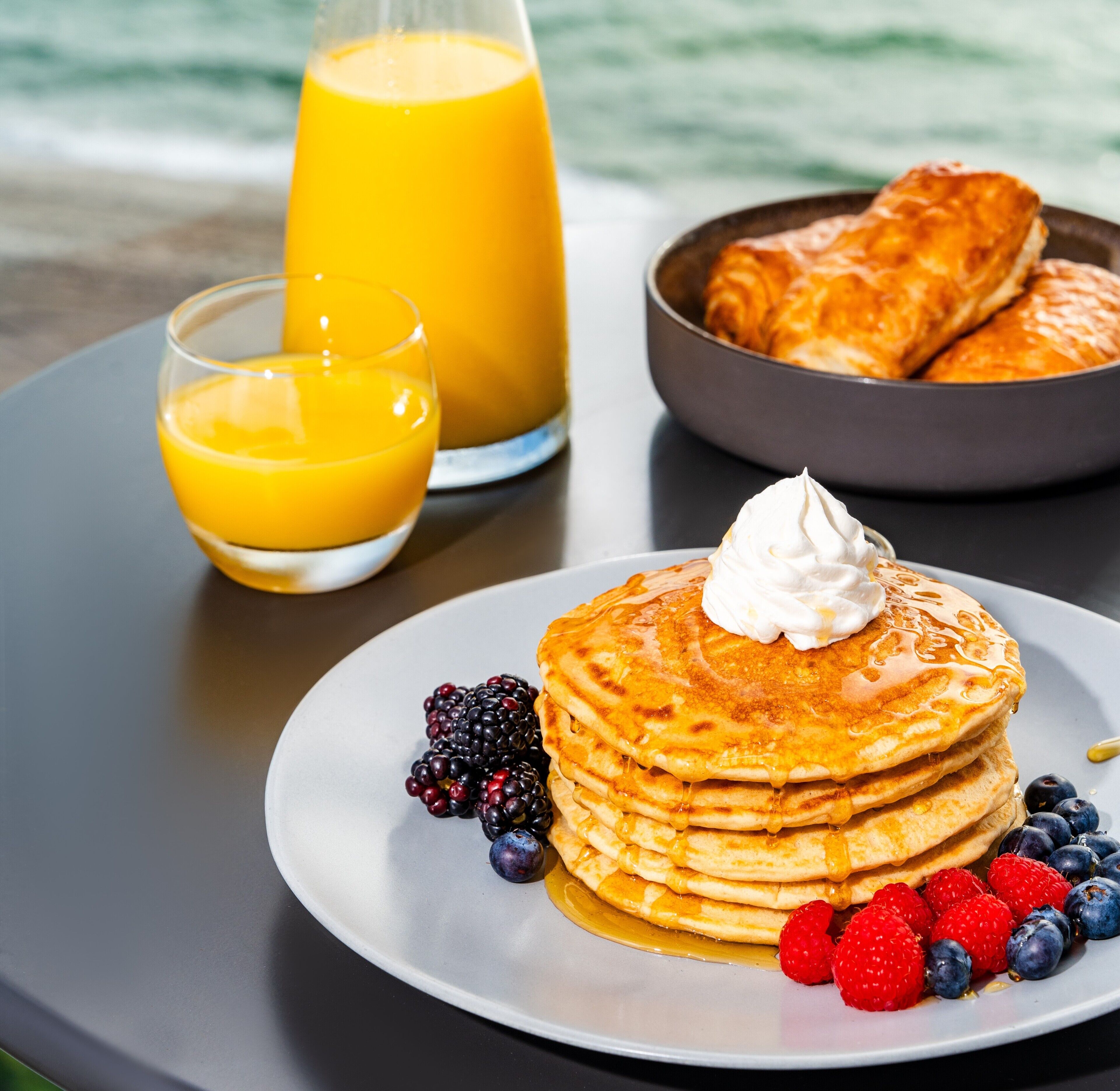 Une assiette de petit-déjeuner avec des crêpes, des fruits rouges et du sirop.