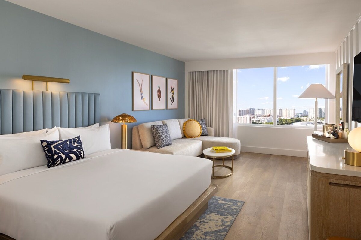 A hotel room with two beds, a sofa, a small table, and a TV.