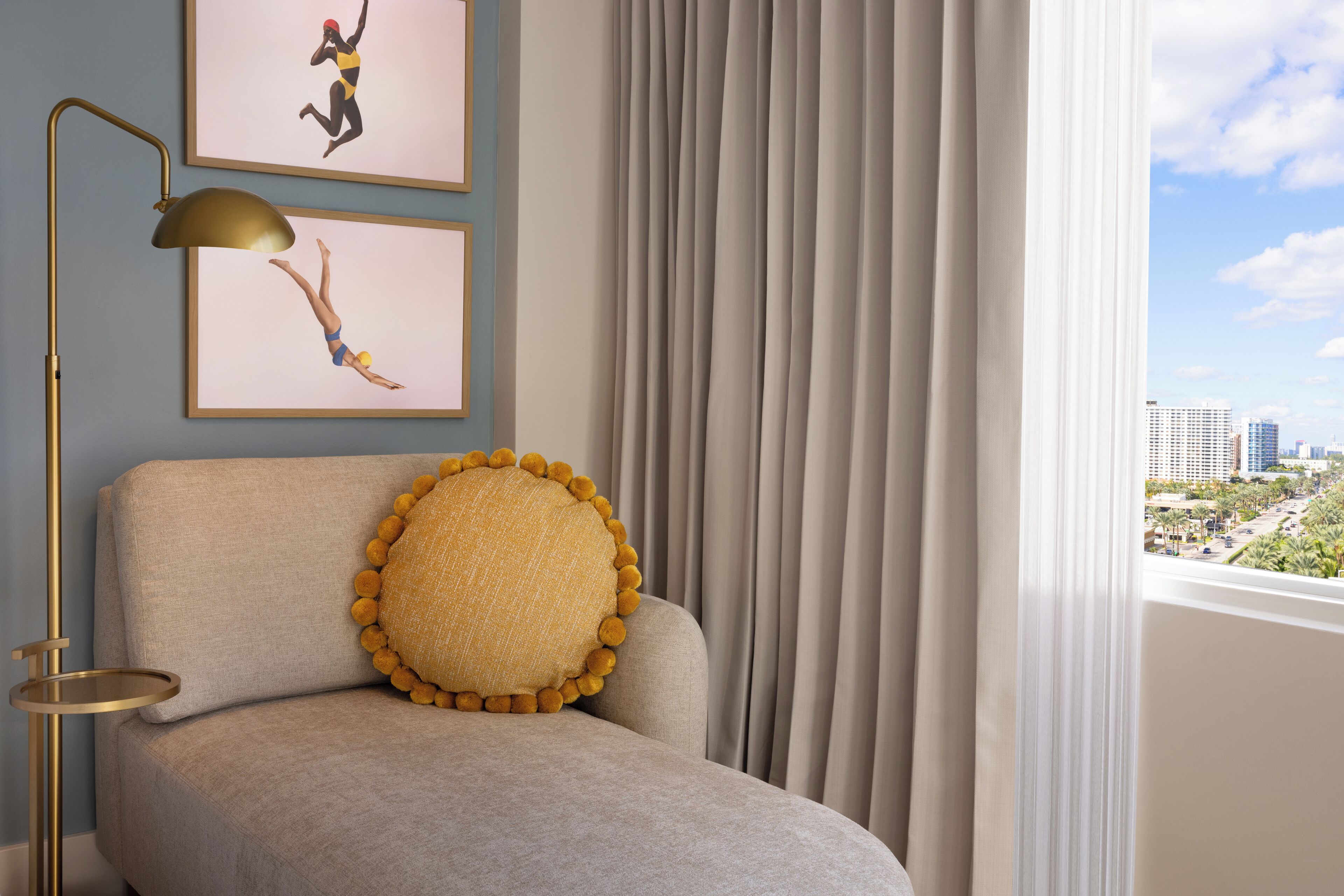 A room with a sofa, a lamp, and two framed pictures on the wall.