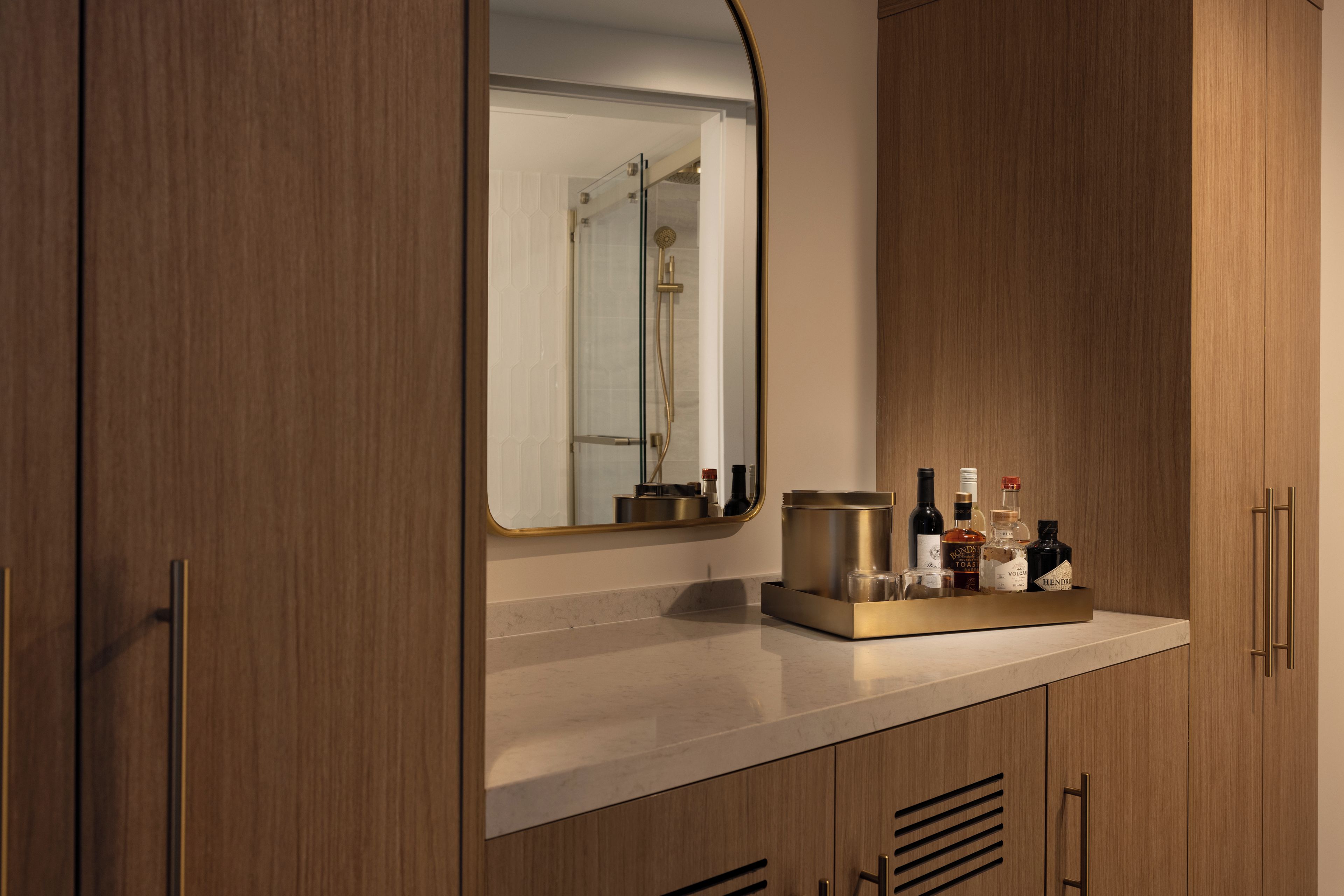 A bathroom with a wooden vanity, a mirror, and a shelf with toiletries.