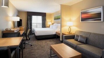 Una habitación de hotel con una cama, un escritorio con teléfono, un sofá, una mesa de centro y un televisor.