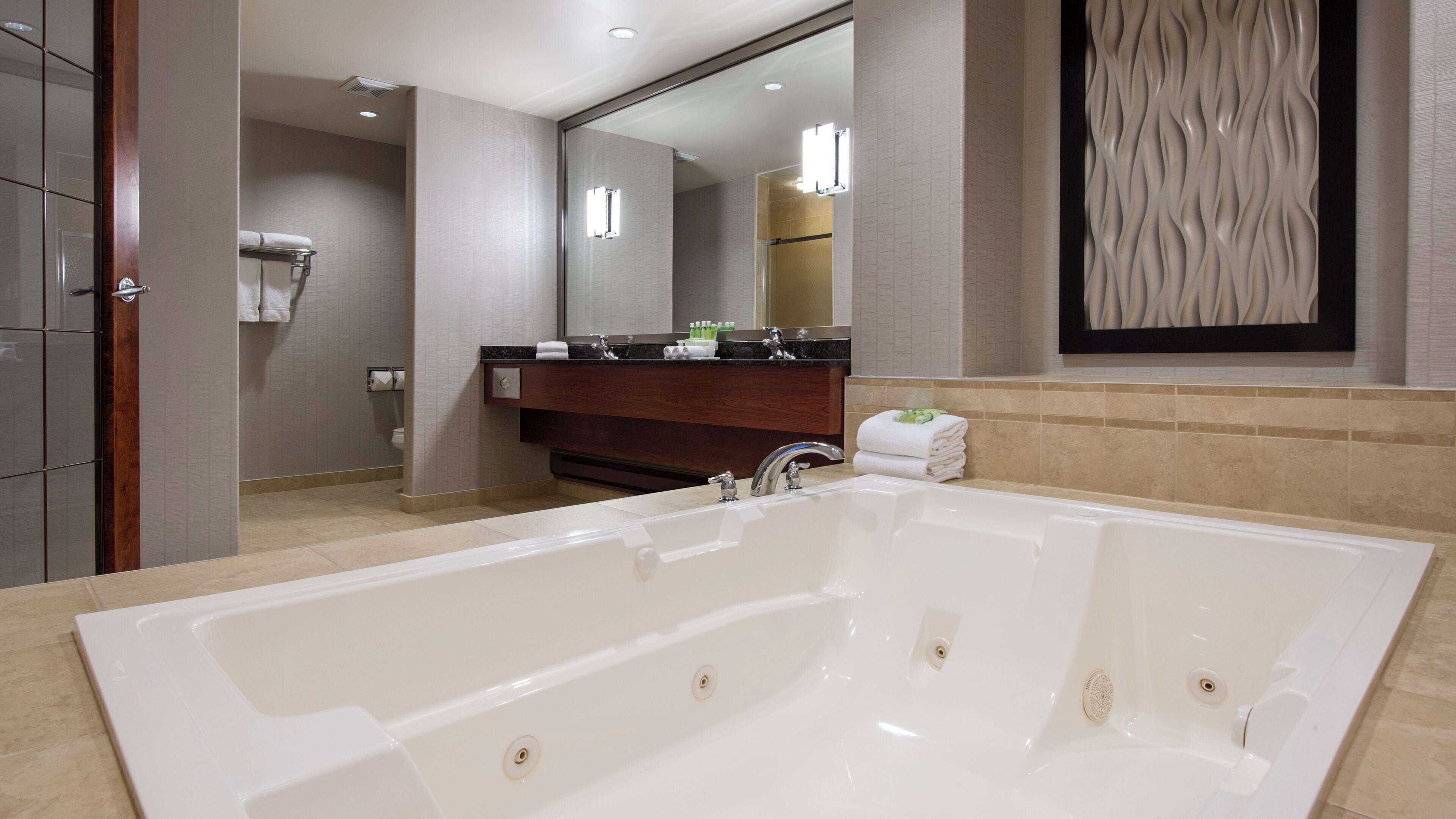 A modern bathroom with a large bathtub, a vanity with a mirror, and a shower area.