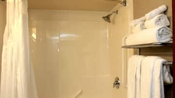 A shower area with a glass door, a towel rack with folded towels, and a showerhead.