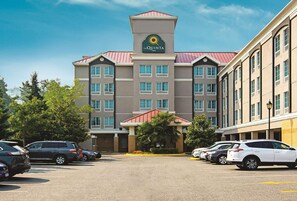 Un hotel La Quinta Inn con entrada central, varios pisos y un estacionamiento con coches.