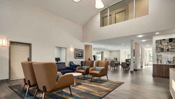Amplio espacio de sala con techo alto, muebles modernos y una cocina al fondo.