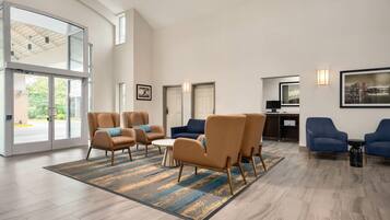 A spacious lobby with modern furniture, large windows, and a cityscape view.