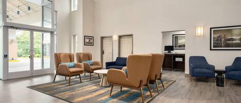 A spacious lobby with modern furniture, large windows, and a cityscape view.