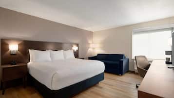Una habitación de hotel con una cama grande, un escritorio, una silla, un sofá y una lámpara.