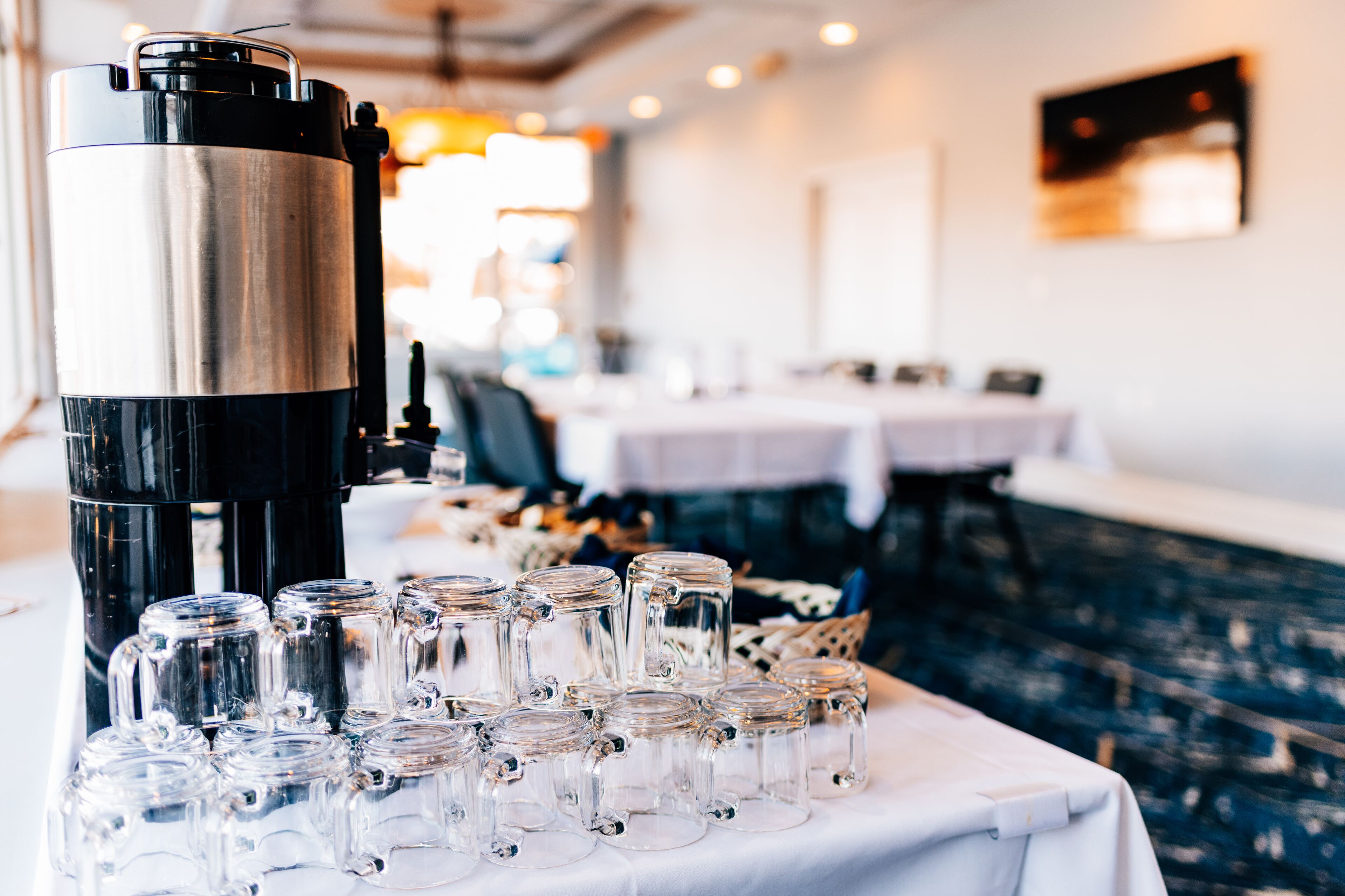 A coffee machine and several glass mugs on a table in a restaurant setting.