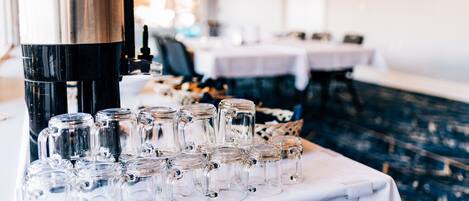 A coffee machine and several glass mugs on a table in a restaurant setting.