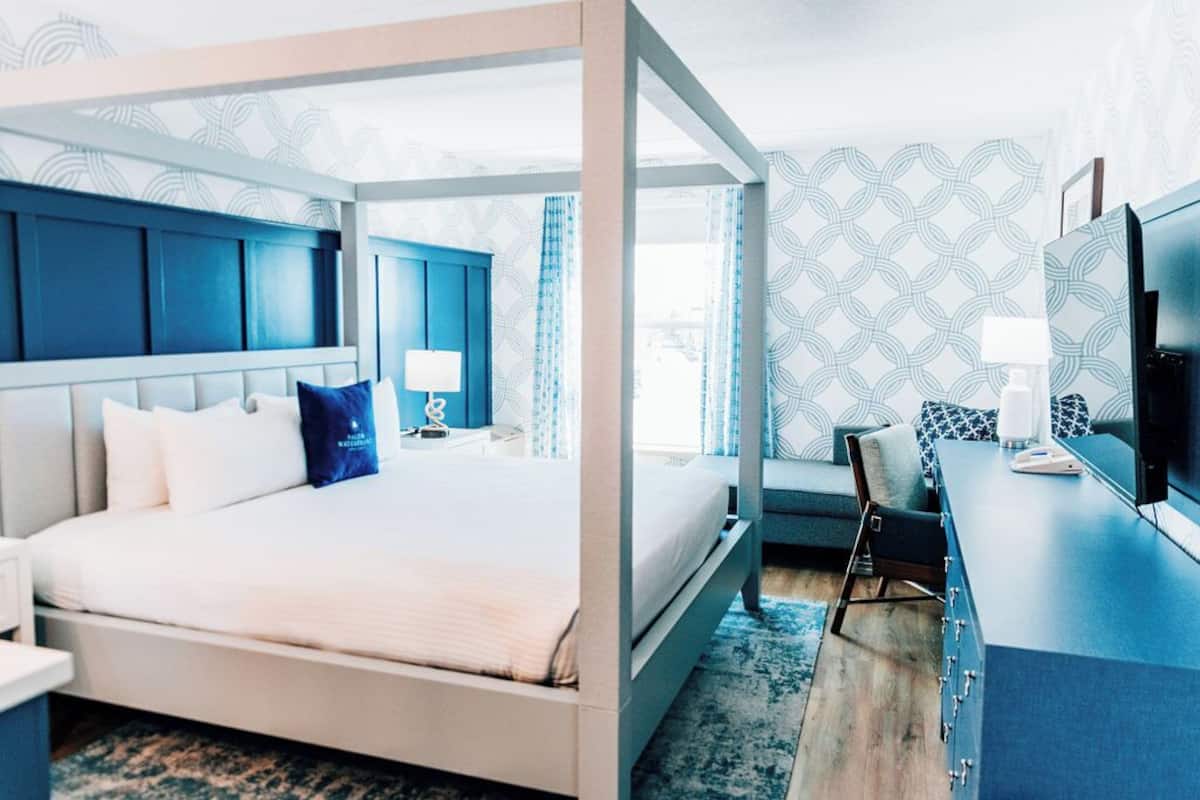 Una habitación de hotel moderna con una cama con dosel, un escritorio y un televisor.