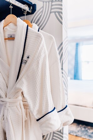 A white robe with a blue trim hanging on a wooden hanger. - Salem Waterfront Hotel & Suites (Salem)
