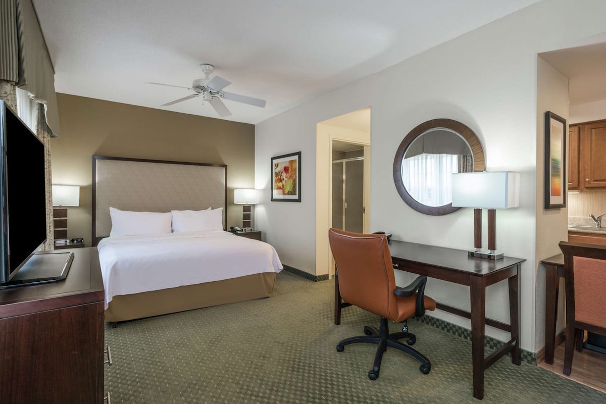 Ein Hotelzimmer mit Bett, Schreibtisch, Stuhl und Deckenventilator.