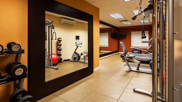 A gym with exercise equipment, a mirror, and a wall-mounted TV.