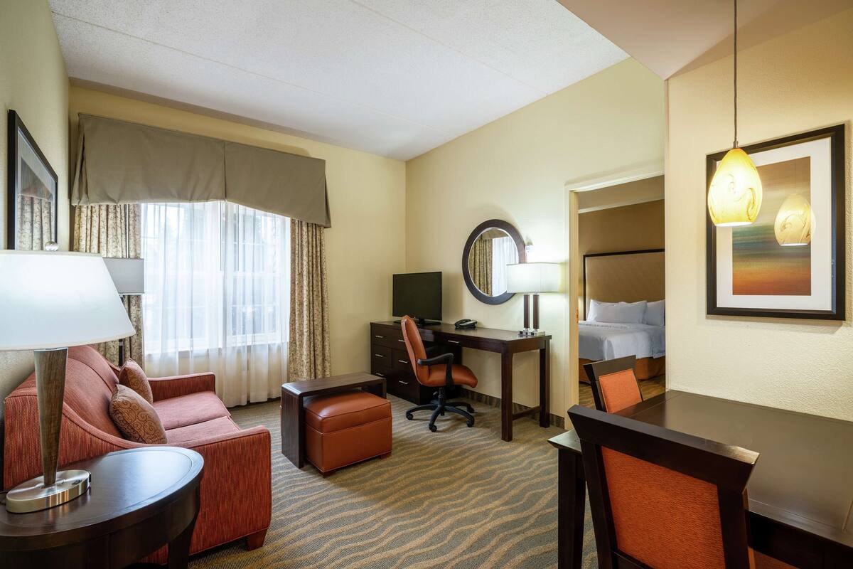 Ein Hotelzimmer mit Bett, Schreibtisch, Stuhl, Sofa und Lampe.