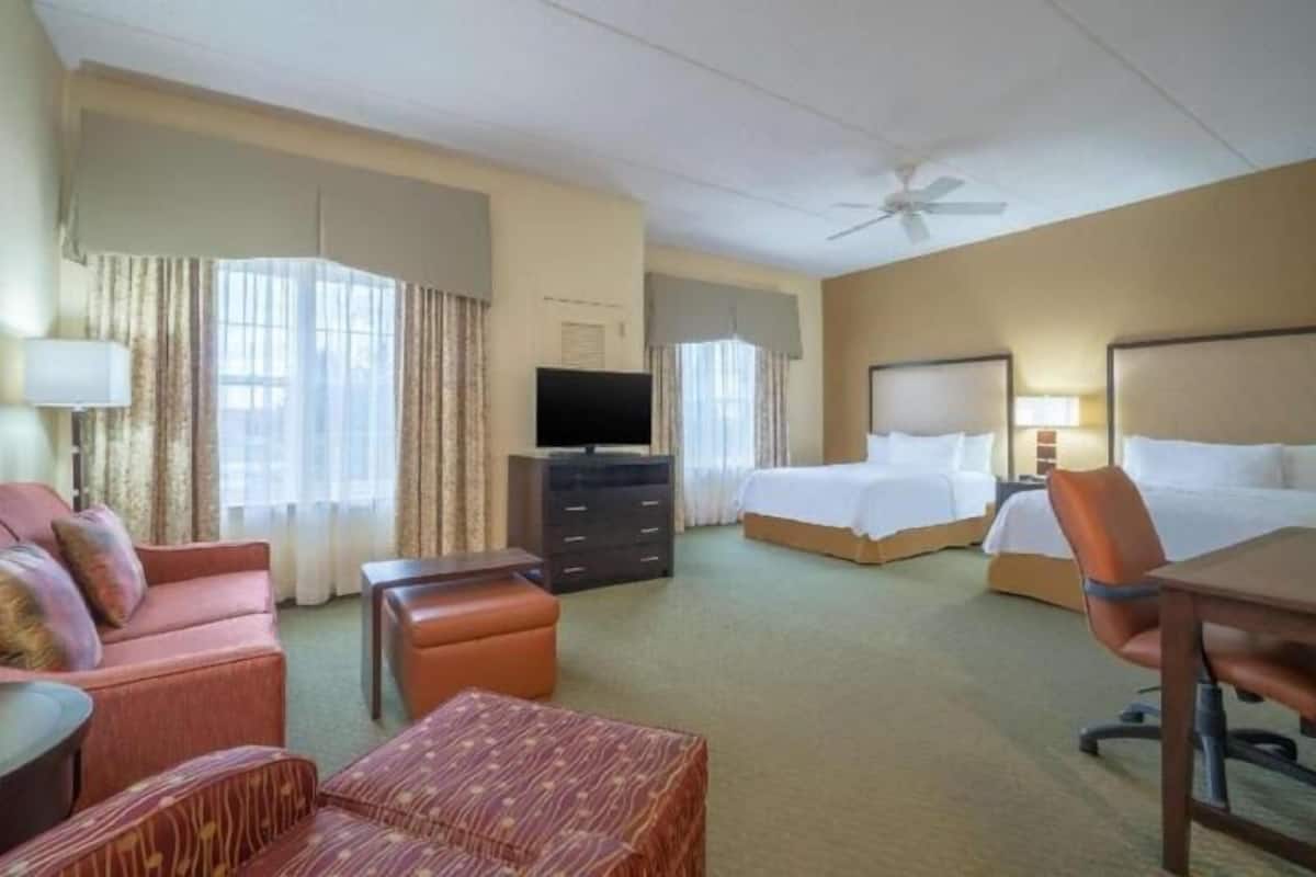 Ein Hotelzimmer mit Bett, Schreibtisch, Stuhl, Fernseher und einer Couch.