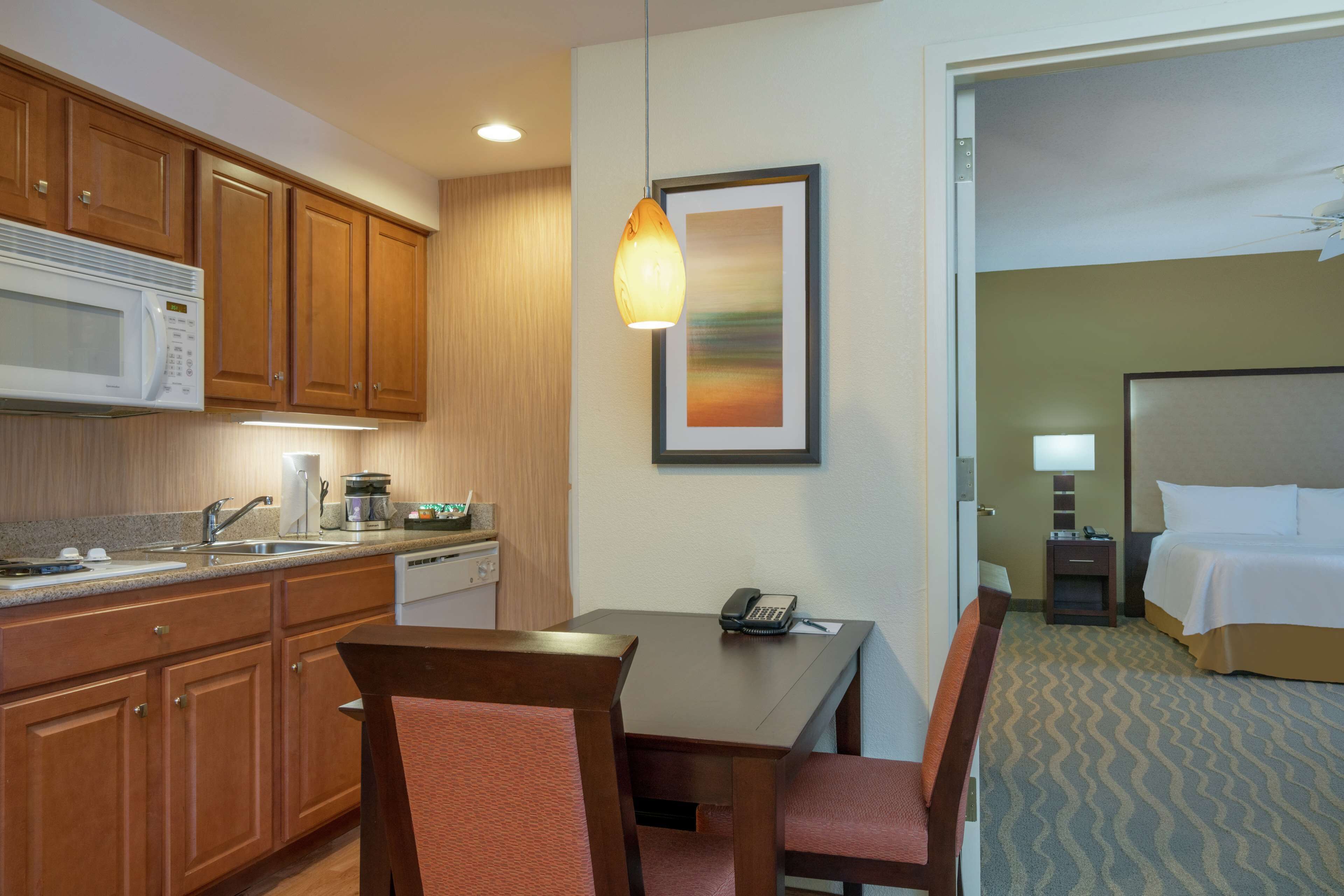 A hotel room with a kitchenette, a dining area, and a bed.