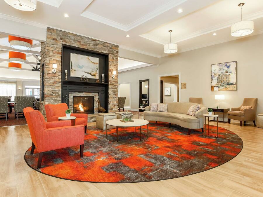 A spacious living room with a fireplace, modern furniture, and a large rug.